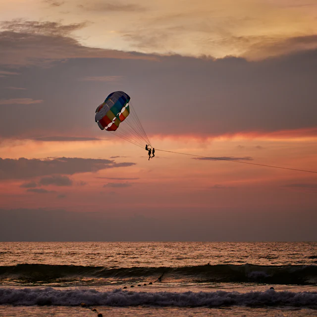 Parasailing against a pink evening sky