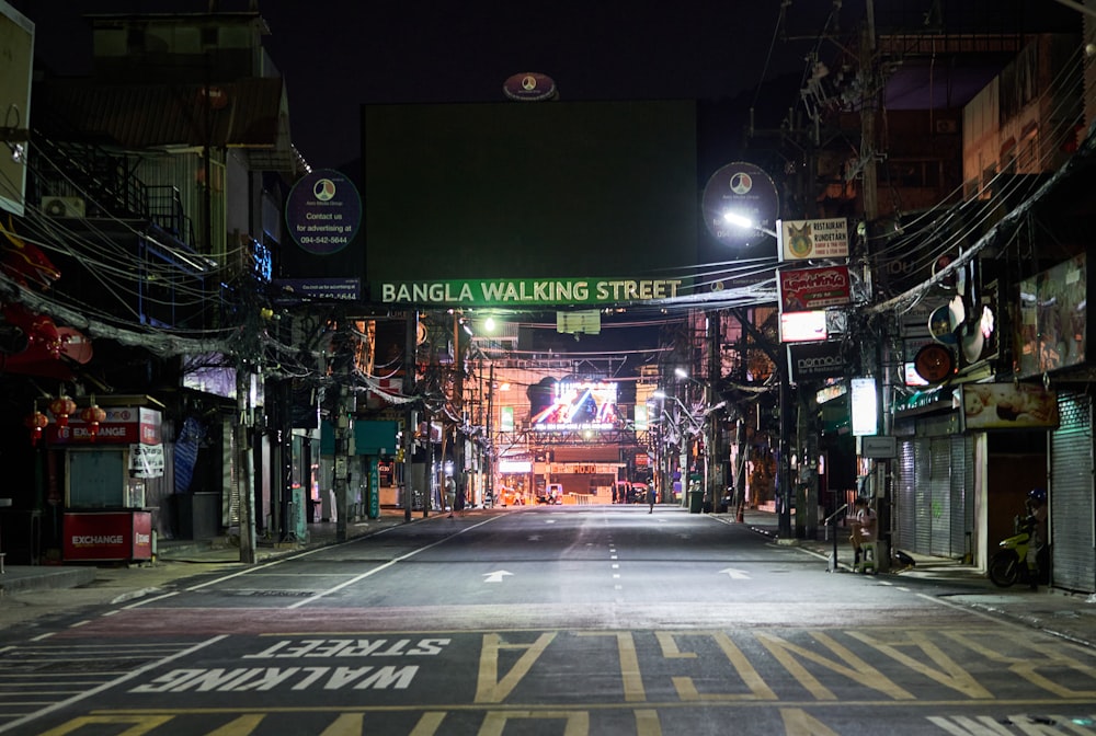 an empty street at night with a neon sign