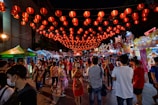 Bustling night market in Thailand glowing with colorful lanterns and lively crowds.