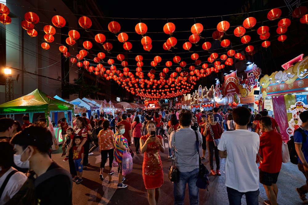 a crowd of people walking down a street under red lanterns
