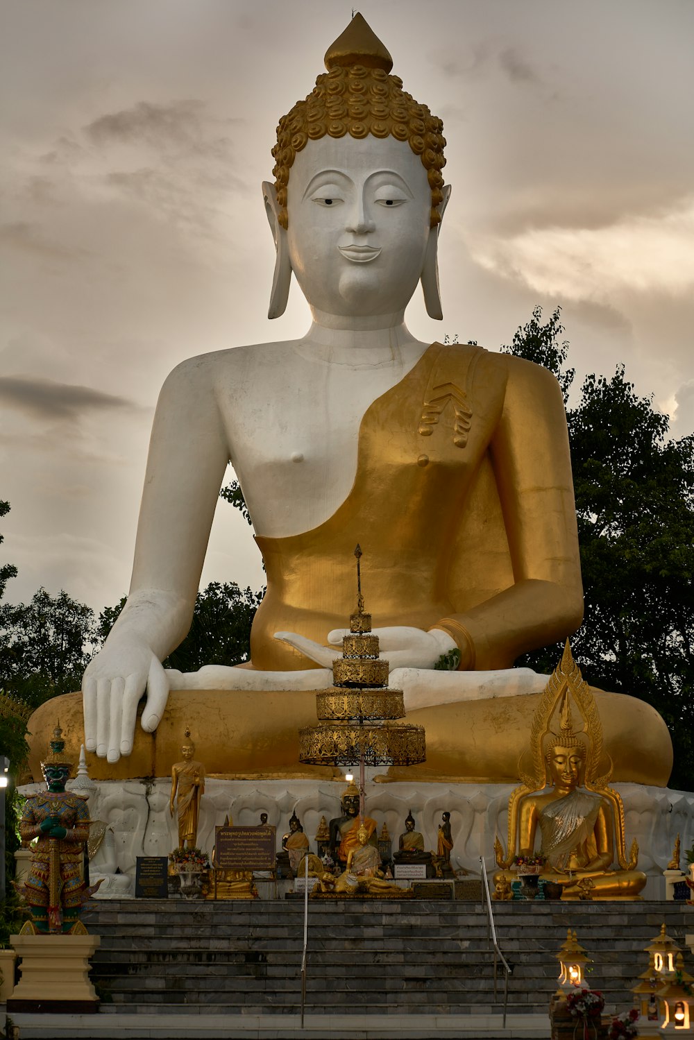 Una grande statua dorata del Buddha seduta in un parco