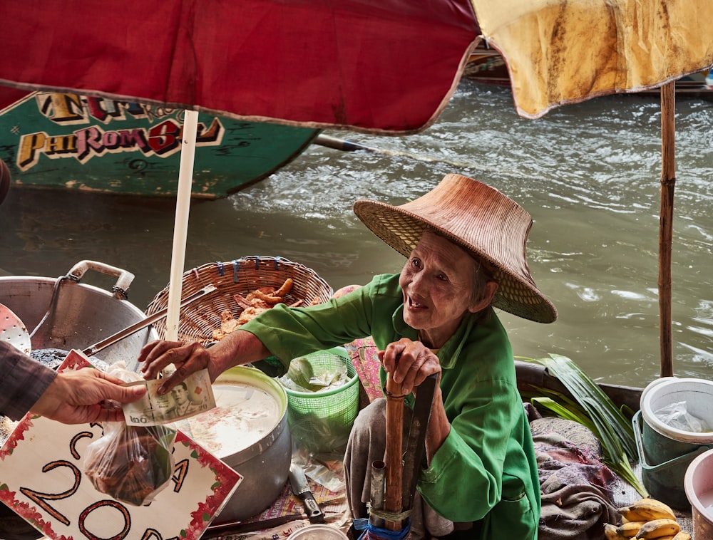 a woman in a straw hat is serving food to another woman