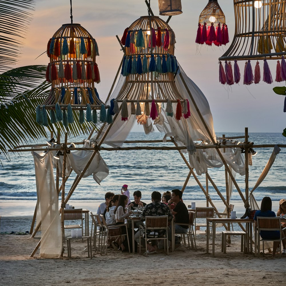 a group of people sitting at a table on the beach