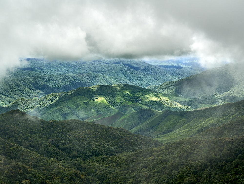 a view of a green mountain range with clouds in the sky