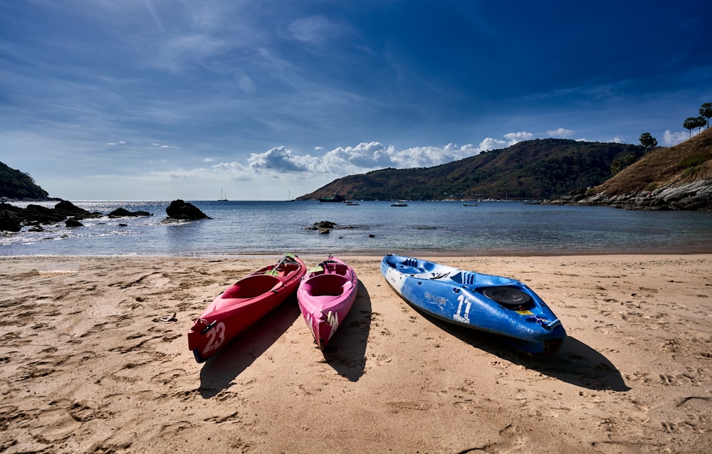two kayaks sitting on a sandy beach next to the ocean