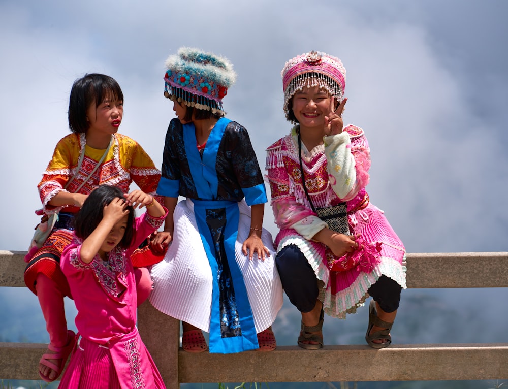 um grupo de meninas sentadas em cima de um banco de madeira