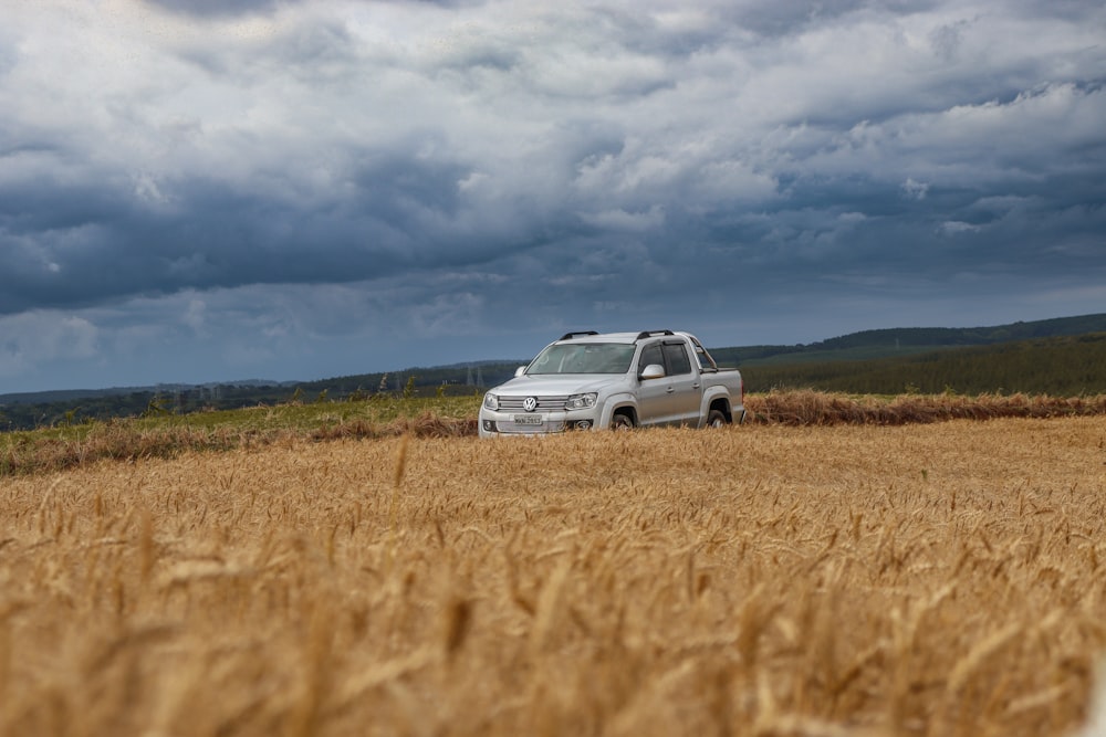 a van parked in a field of wheat under a cloudy sky