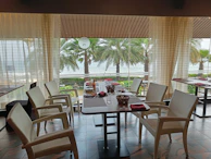 Curtains gently pulled aside to reveal a serene resort dining area overlooking the ocean.