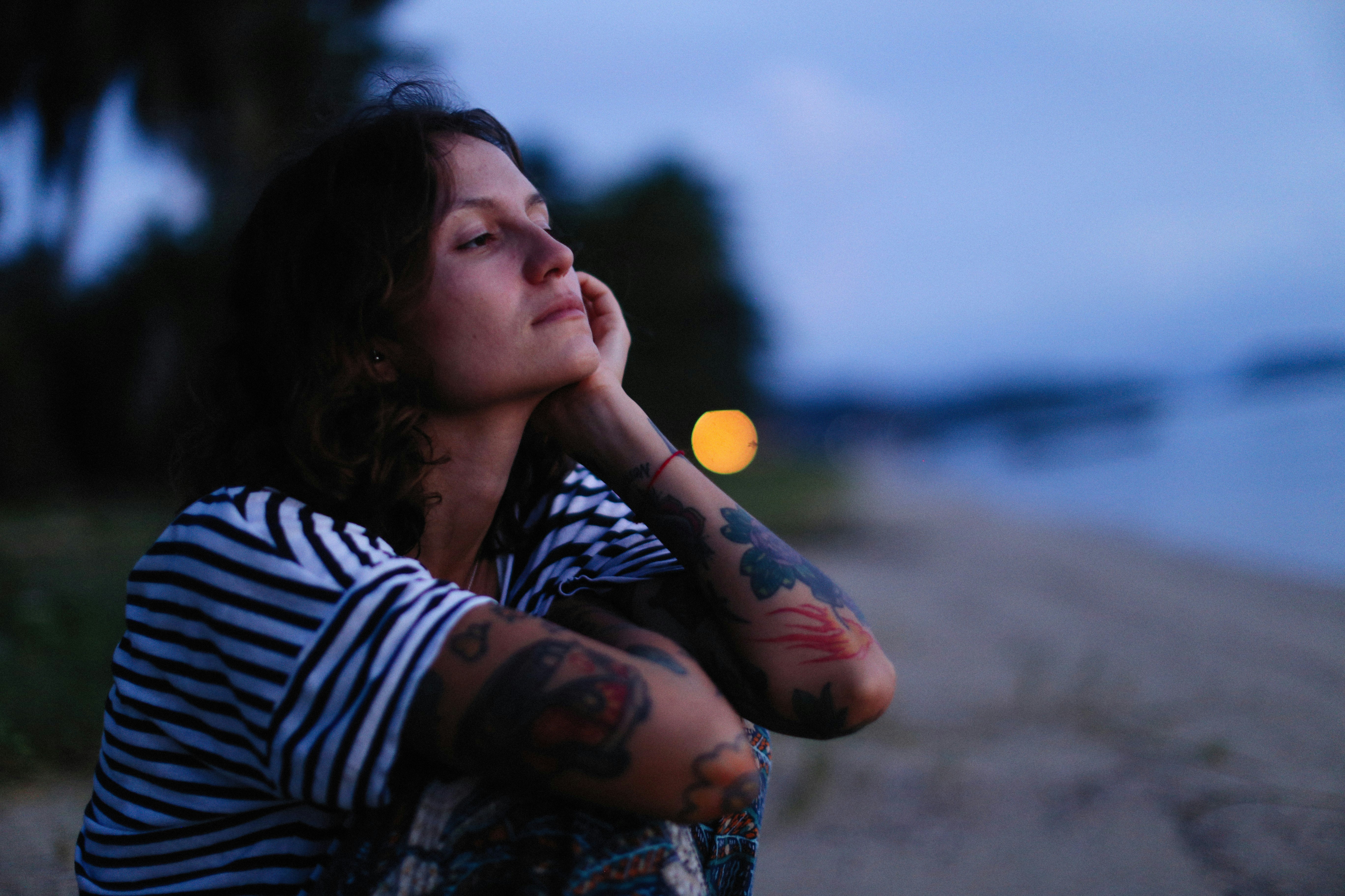 a woman sitting on a beach with her eyes closed