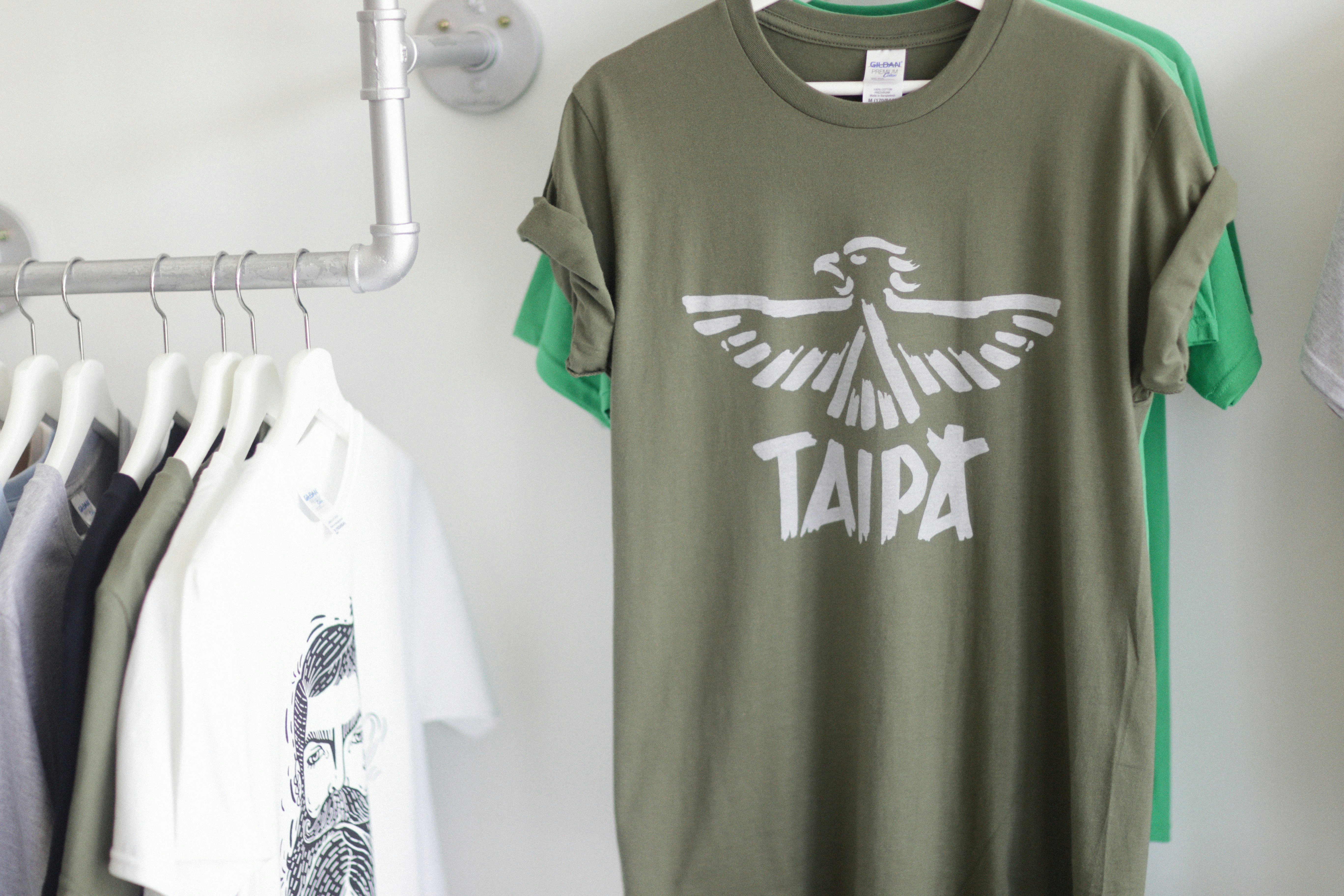 a t - shirt hanging on a rack next to clothes