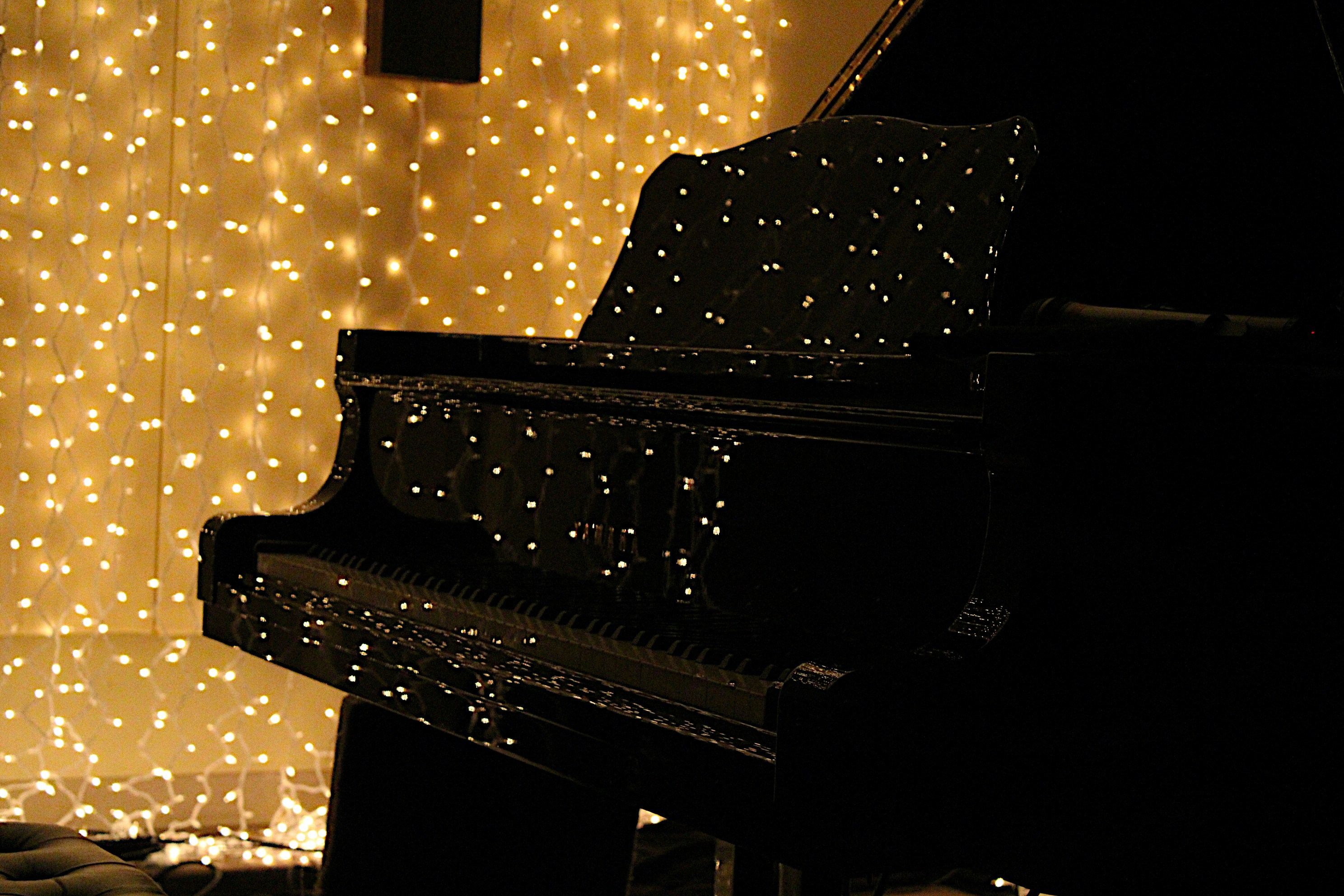 Concert grand piano on empty stage, single spotlight from above, dramatic shadows, dark theatrical atmosphere