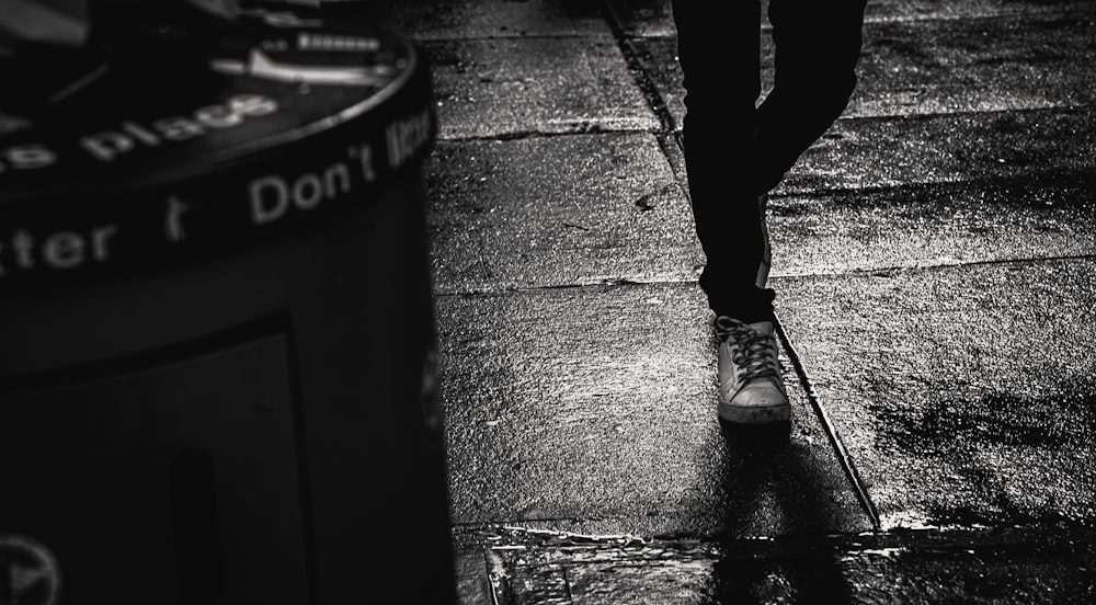 Una persona che cammina lungo un marciapiede sotto la pioggia