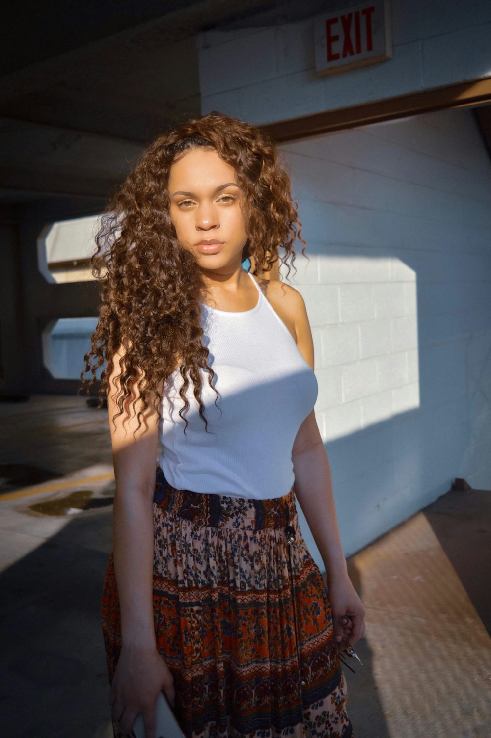 a woman with long curly hair standing in front of a white wall