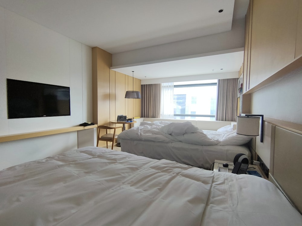 Una camera d'albergo con due letti e TV a schermo piatto