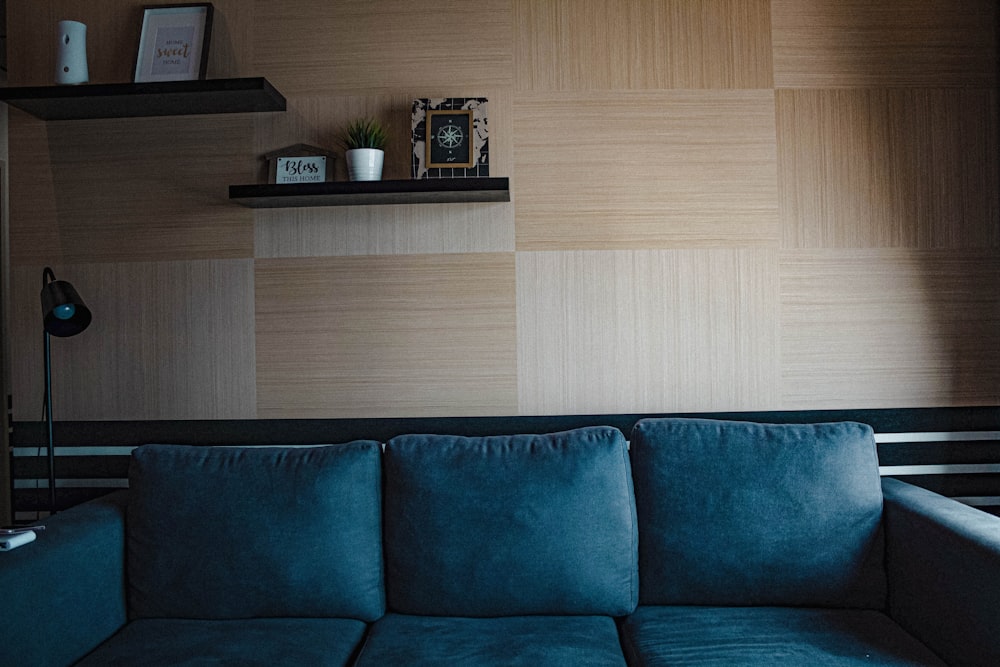 a blue couch sitting in a living room next to a window