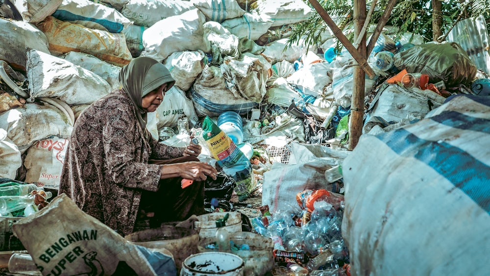 a man sitting in a pile of garbage next to a tree
