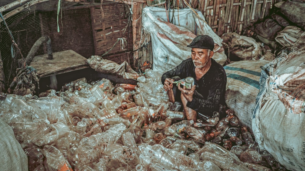 um homem sentado em uma pilha de sacos plásticos