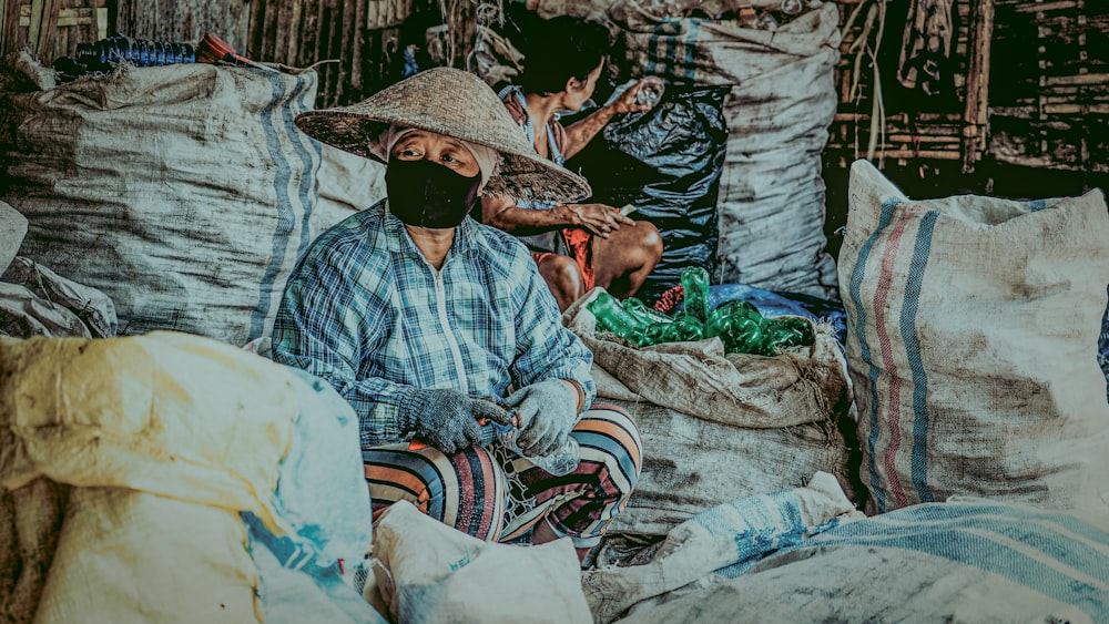 a man wearing a face mask sitting on a pile of bags