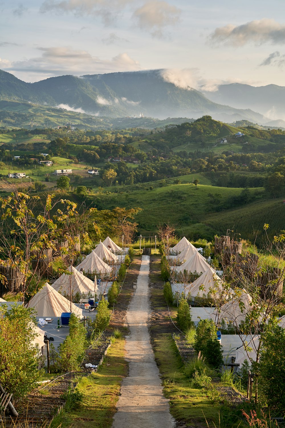 a dirt road leading to tents in the mountains