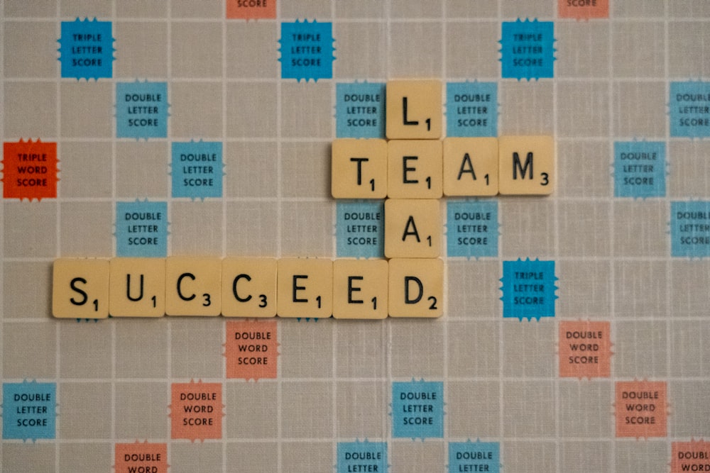 Scrabble board with words: Lead, Team, Succeed