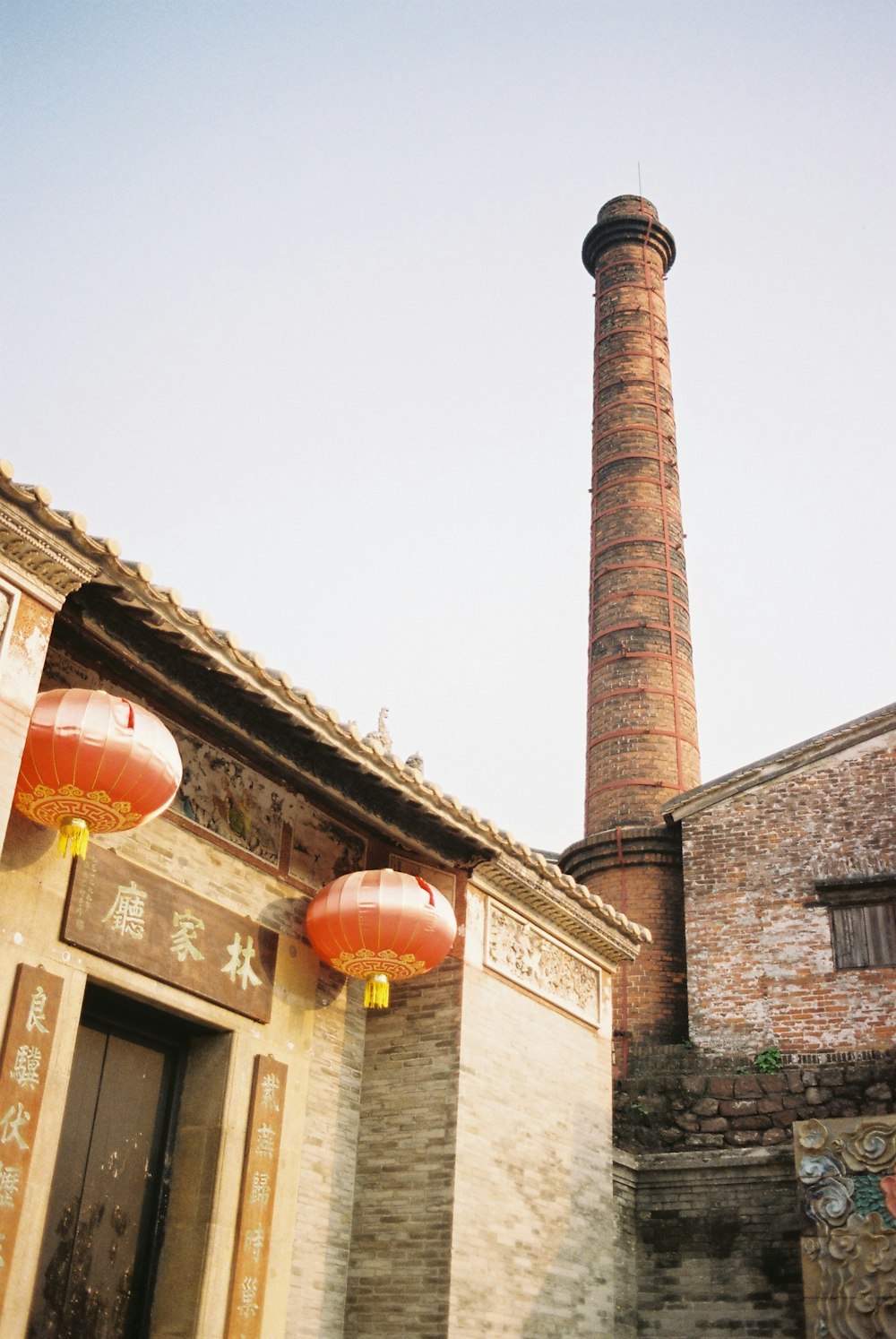 two red lanterns hanging from the side of a brick building