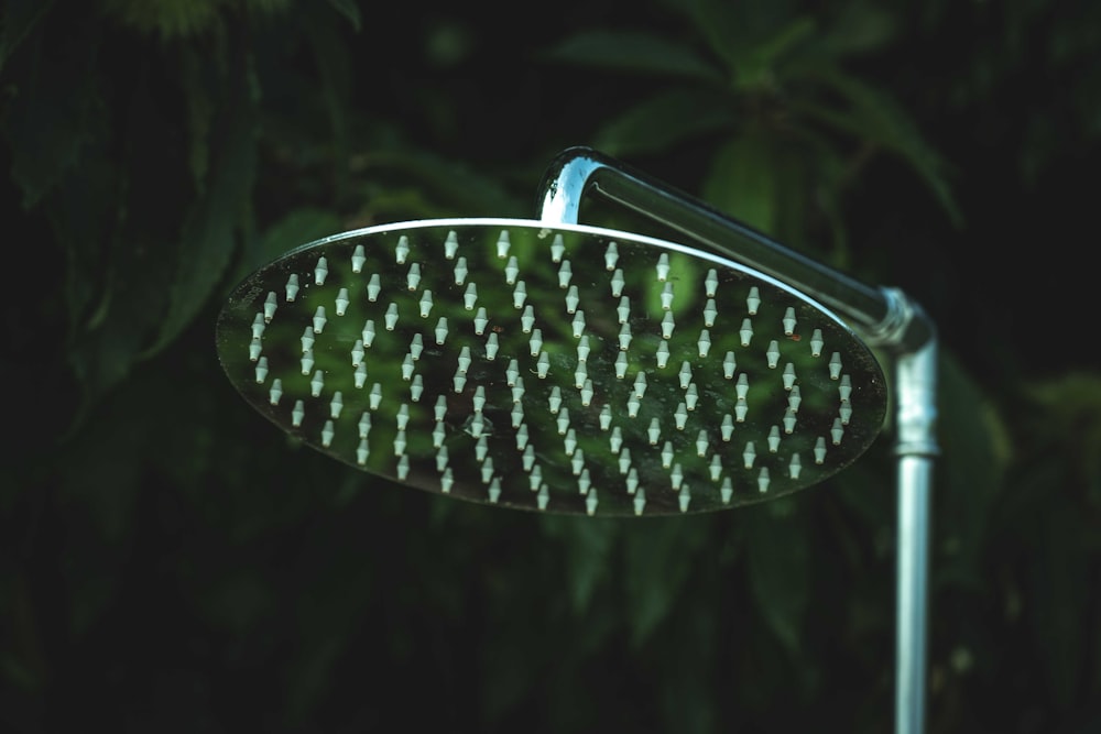 a close up of a shower head in front of trees