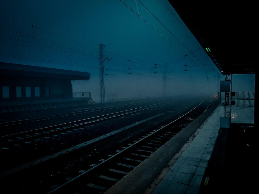 a foggy train station with a train on the tracks