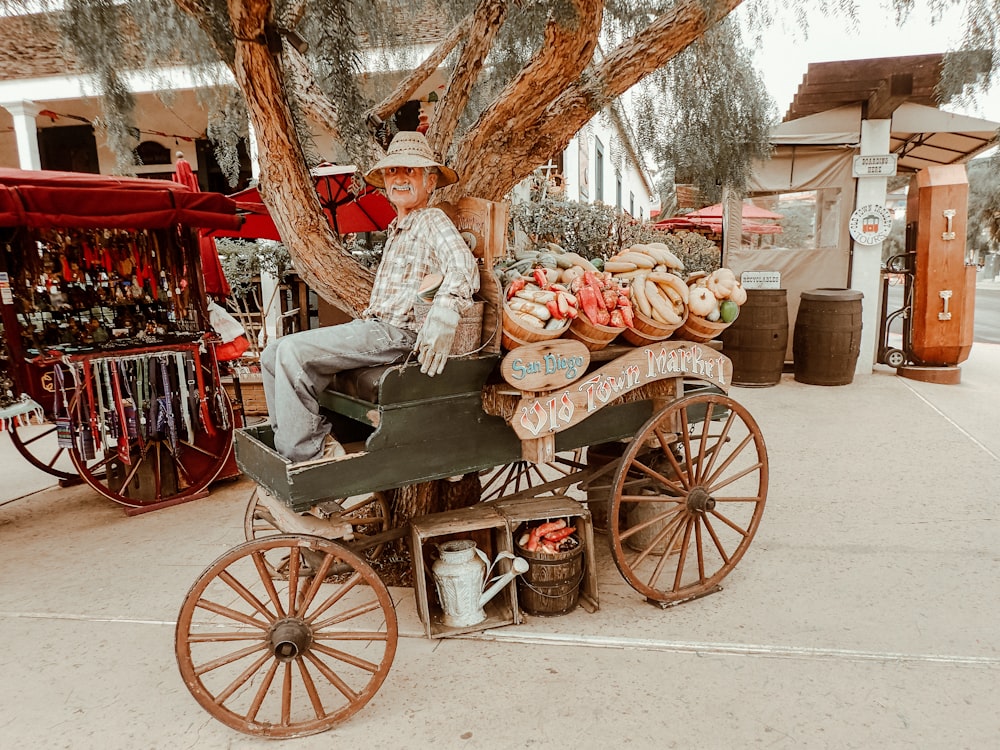 Un hombre sentado encima de un carrito lleno de comida