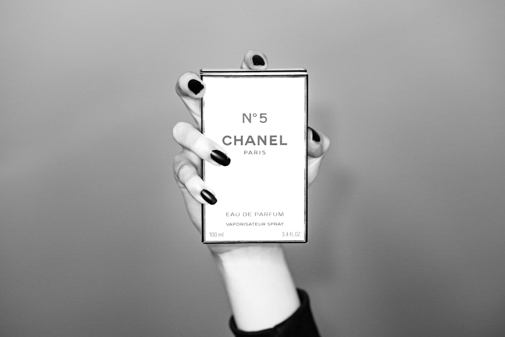 a woman holding up a box of chanel nail polish