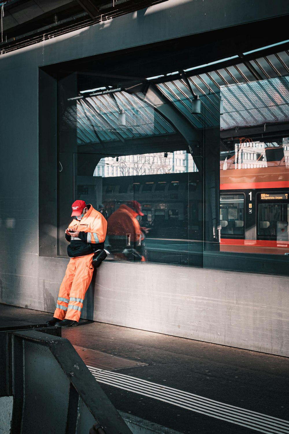 a man in an orange safety suit leaning against a wall