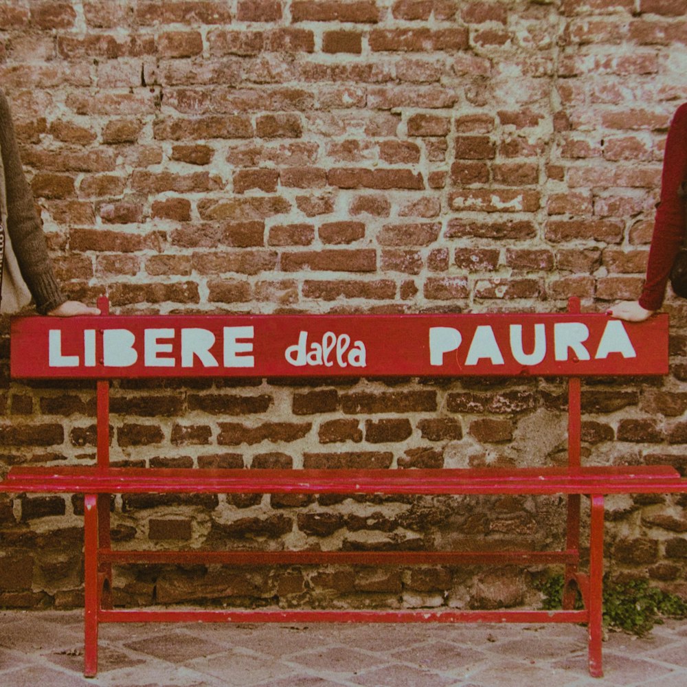 a red bench sitting next to a brick wall