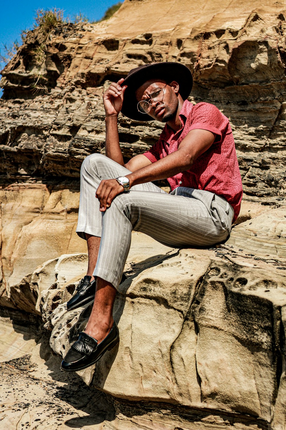 a man sitting on a rock wearing a hat