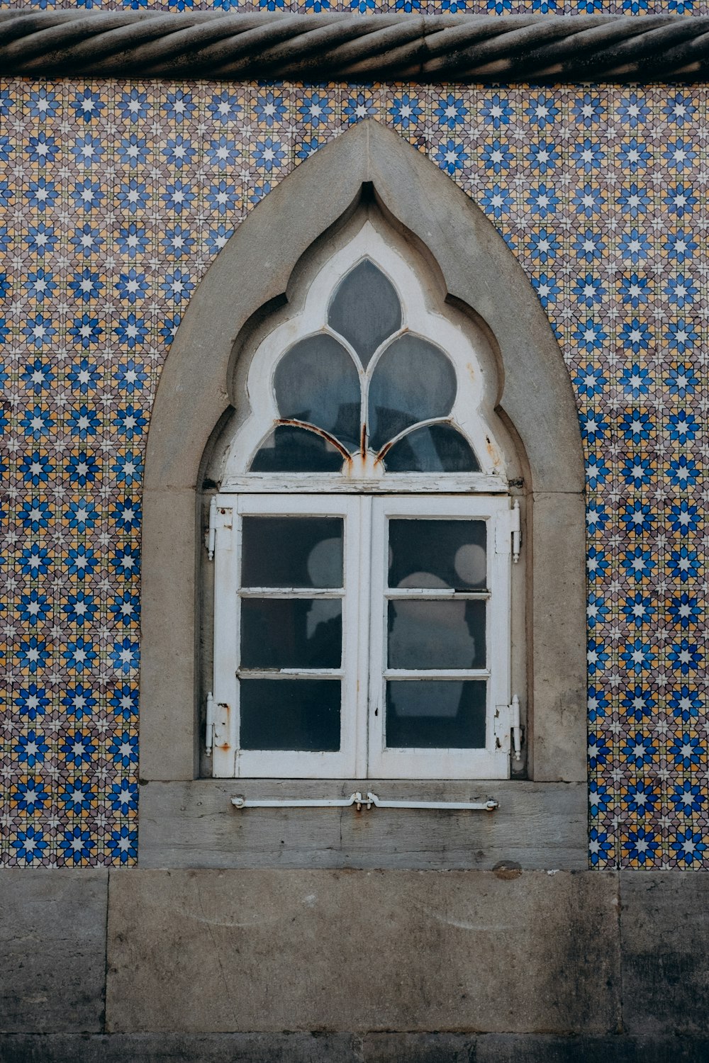 a window in a wall with blue and white tiles