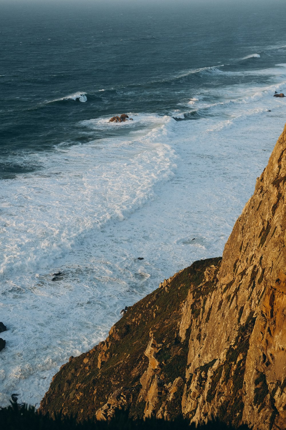 a person standing on top of a cliff next to the ocean