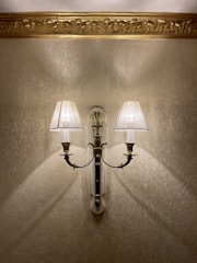 A warm-lit vintage brass sconce mounted on a textured wall.