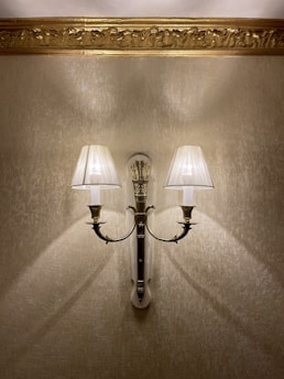 A warm-lit vintage brass sconce mounted on a textured wall.