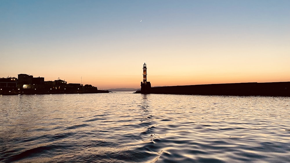 a body of water with a light tower in the distance