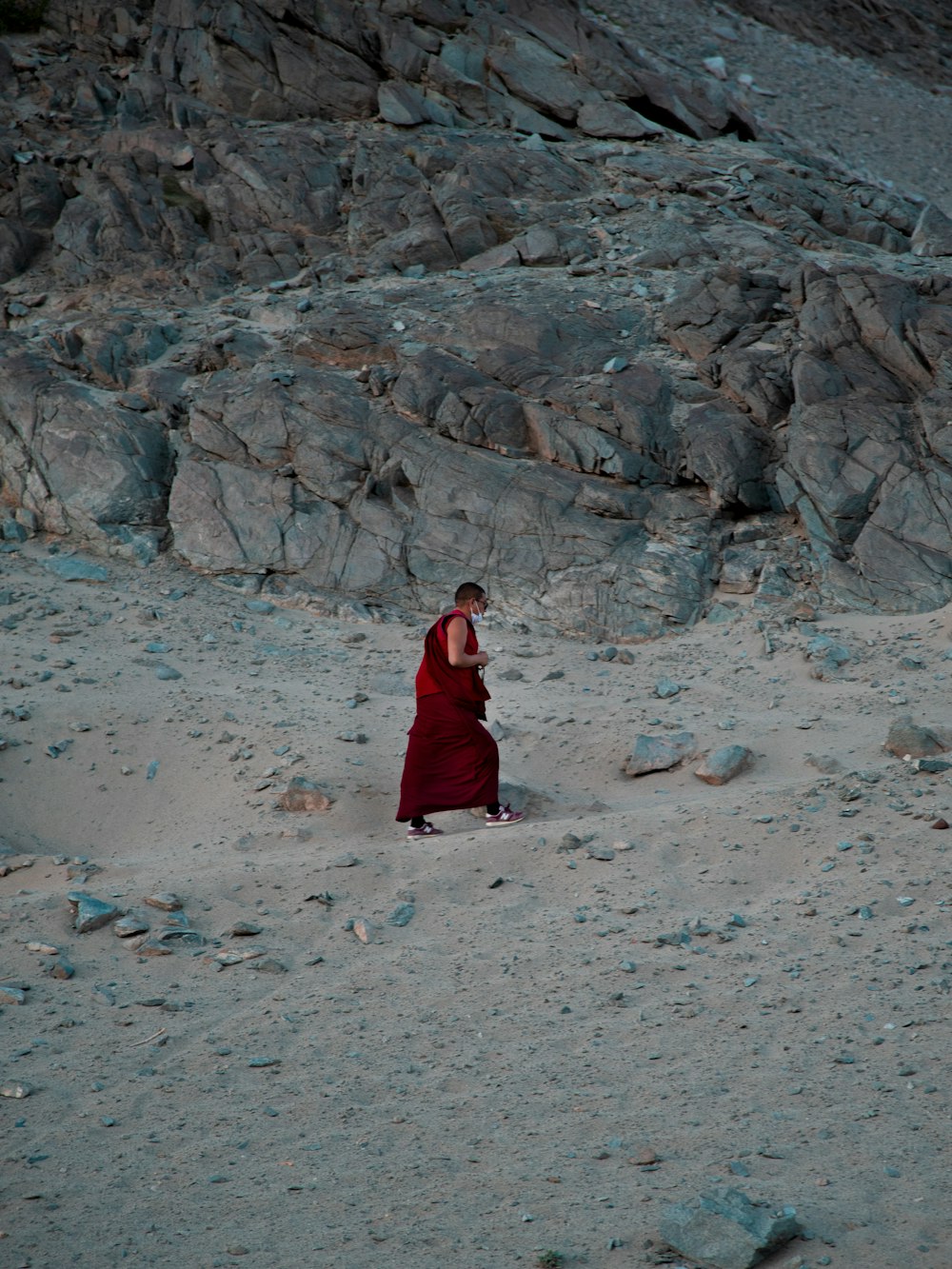 a monk in a red robe standing in the sand