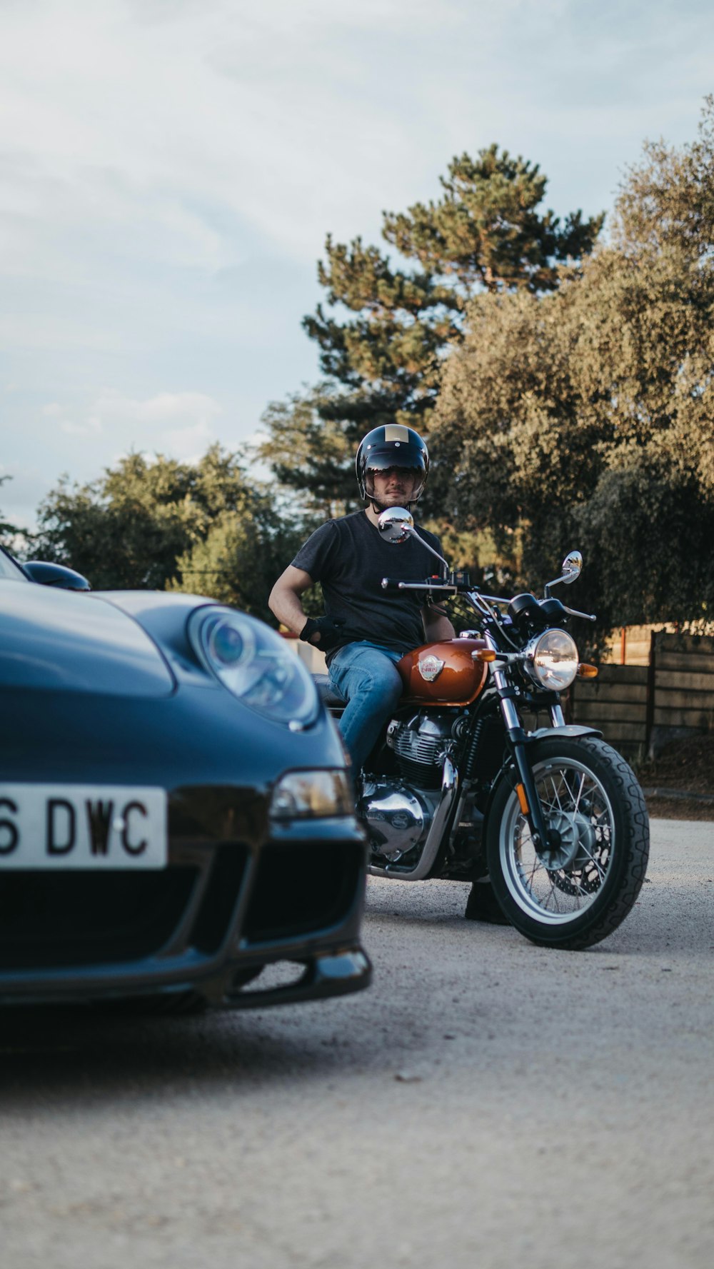 a man riding on the back of a motorcycle next to a blue sports car