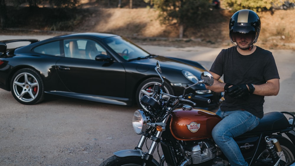 a man sitting on a motorcycle next to a car