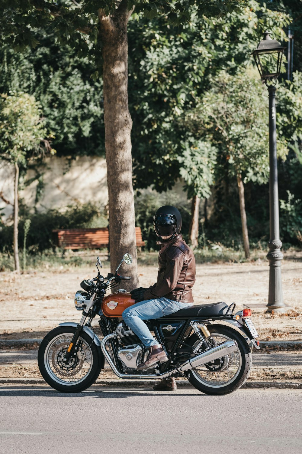 a man riding a motorcycle down a street next to a tree