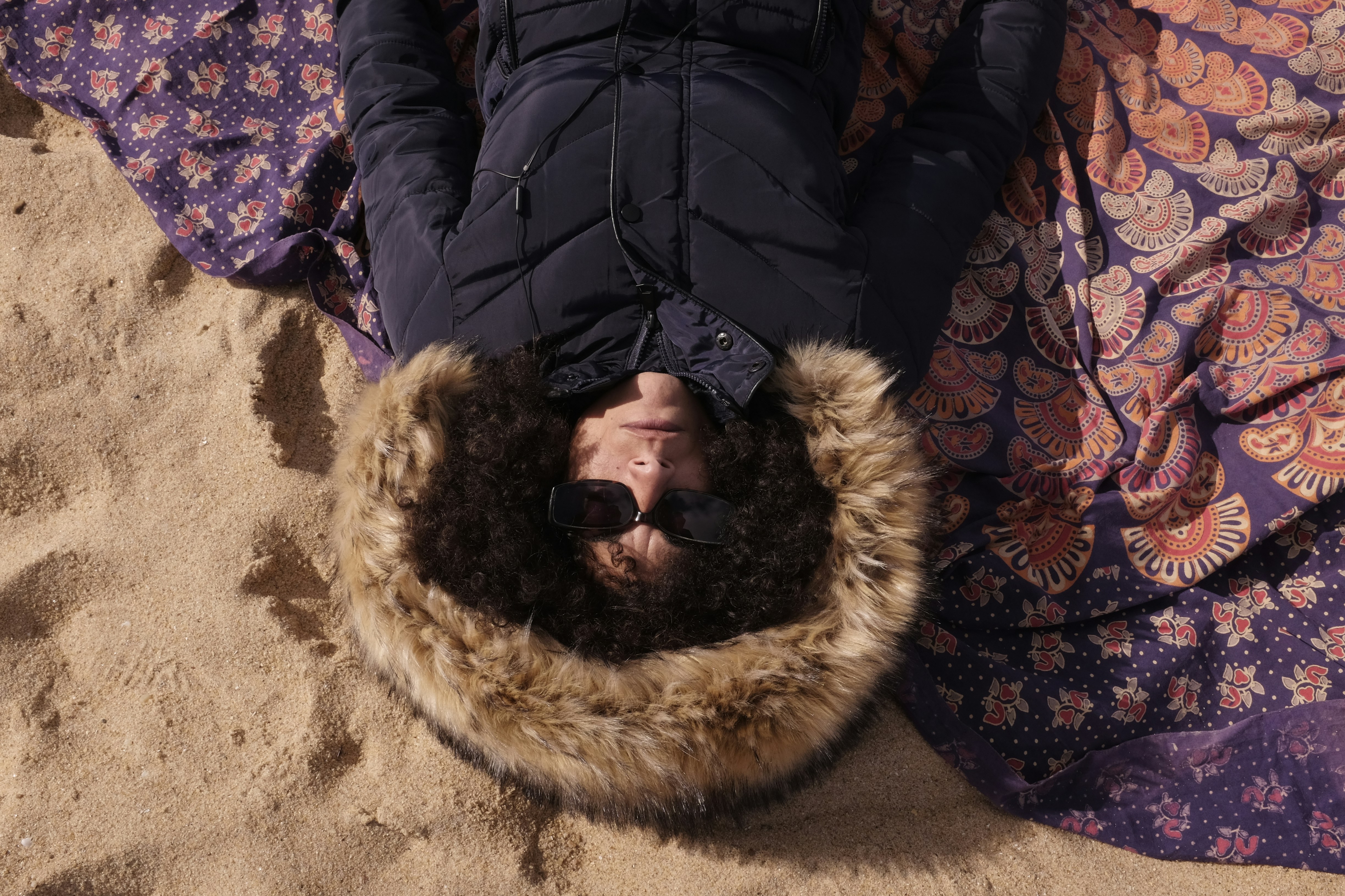겨울철 플리스 후드티 추천 - a person laying on top of a blanket on a beach