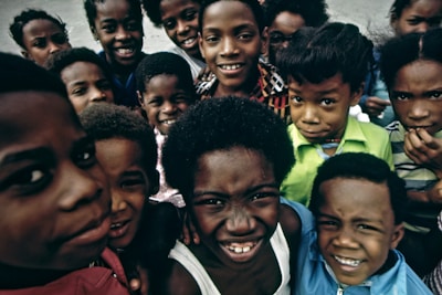 A group of smiling children playing together in a sunlit field.