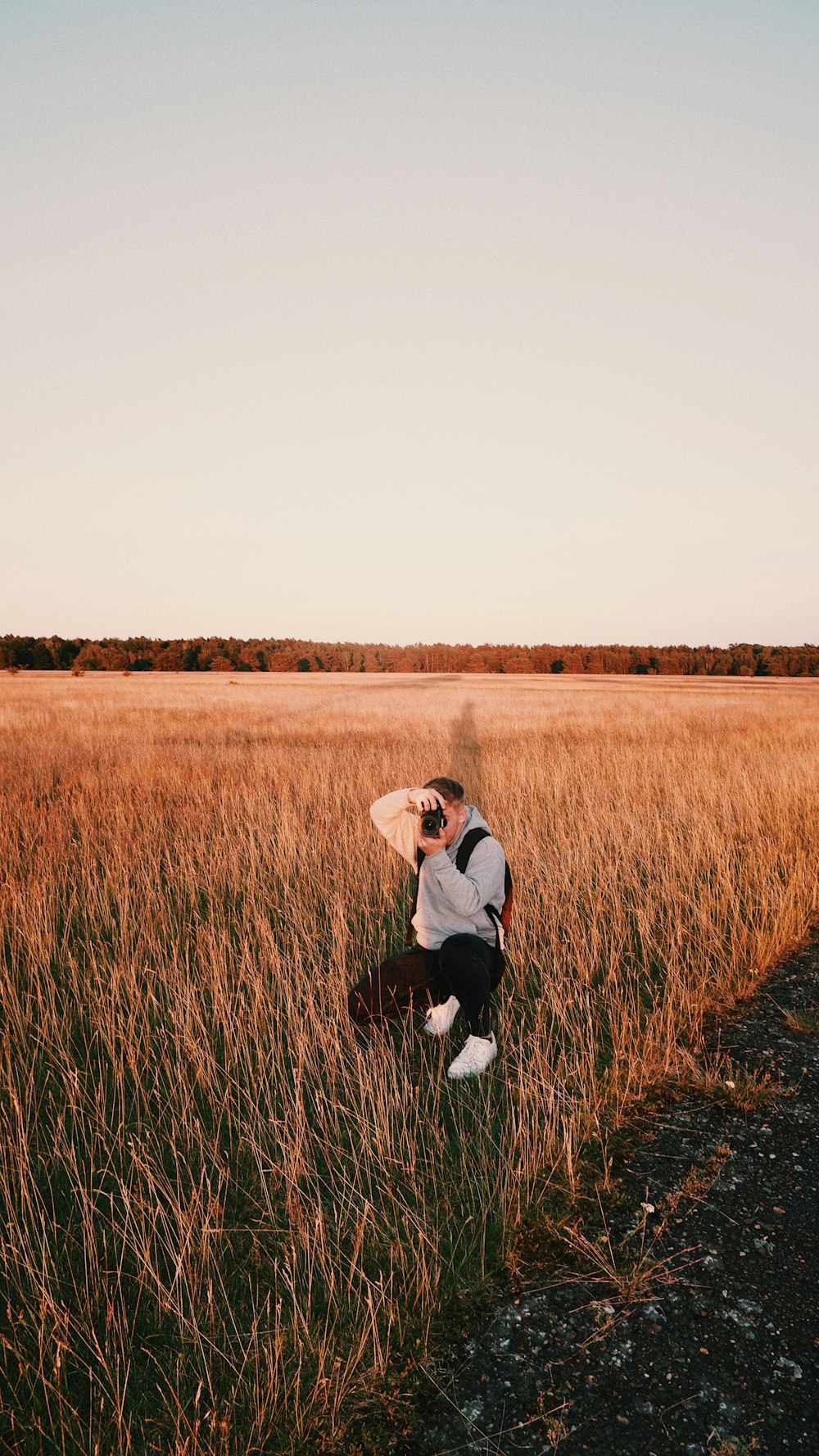 a man kneeling in a field holding a surfboard