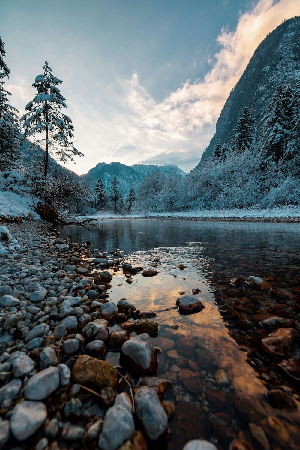 a river surrounded by snow covered mountains and trees