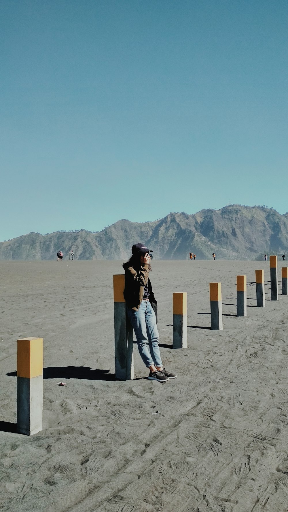 a person leaning against a post in the middle of a desert