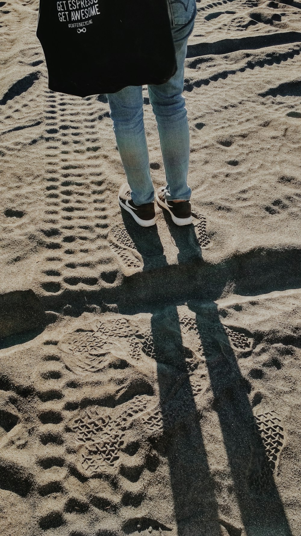 a person holding a black bag in the sand