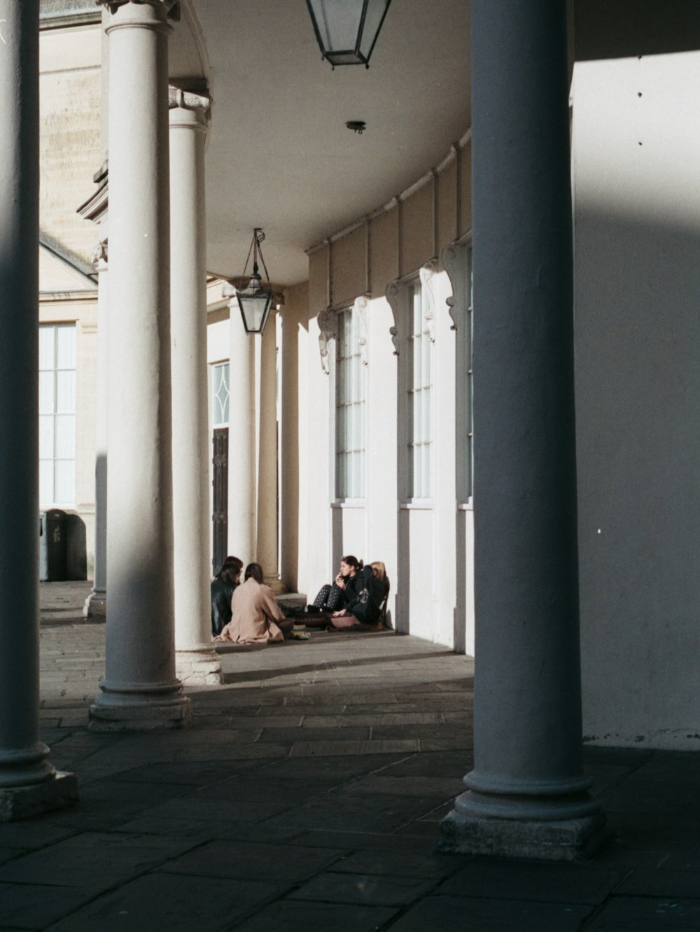 a group of people sitting on the ground under a building