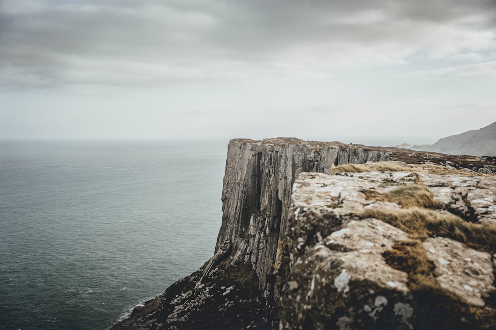 a rocky cliff overlooking the ocean on a cloudy day