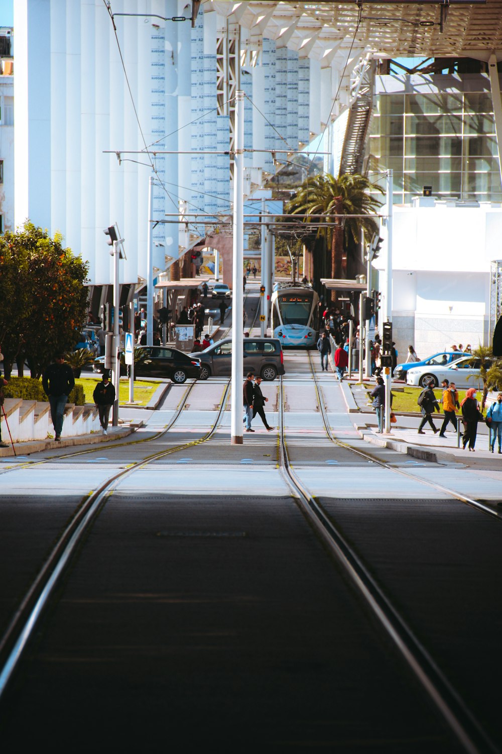 a group of people walking down a street next to a train track